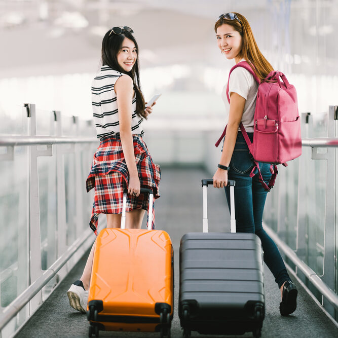 Two,Happy,Asian,Girls,Traveling,Abroad,Together,,Carrying,Suitcase,Luggage